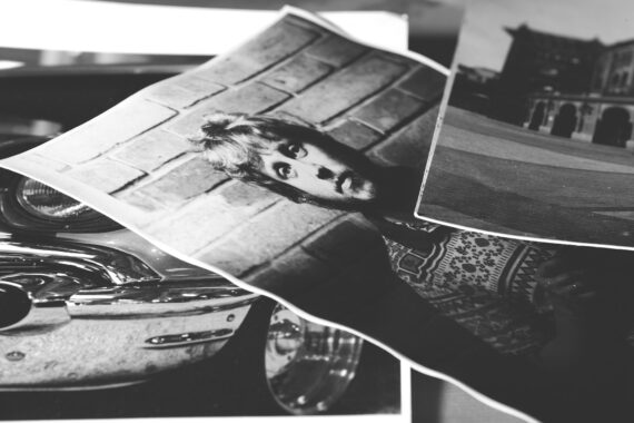 Ein Stapel Schwarz-Weiß-Fotografien mit dem Porträt einer Person vor einer Backsteinmauer, einem Teil eines Oldtimers und einem Gebäude. (KI generierte Beschreibung)